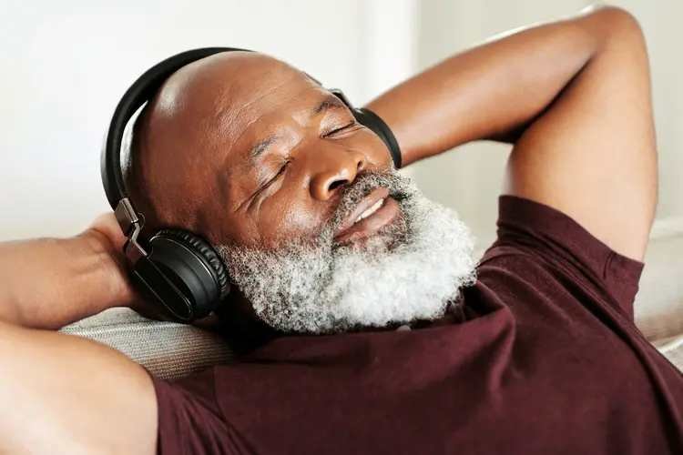Person relaxing on a couch wearing headphones, illustrating the use of binaural beats for brain entrainment