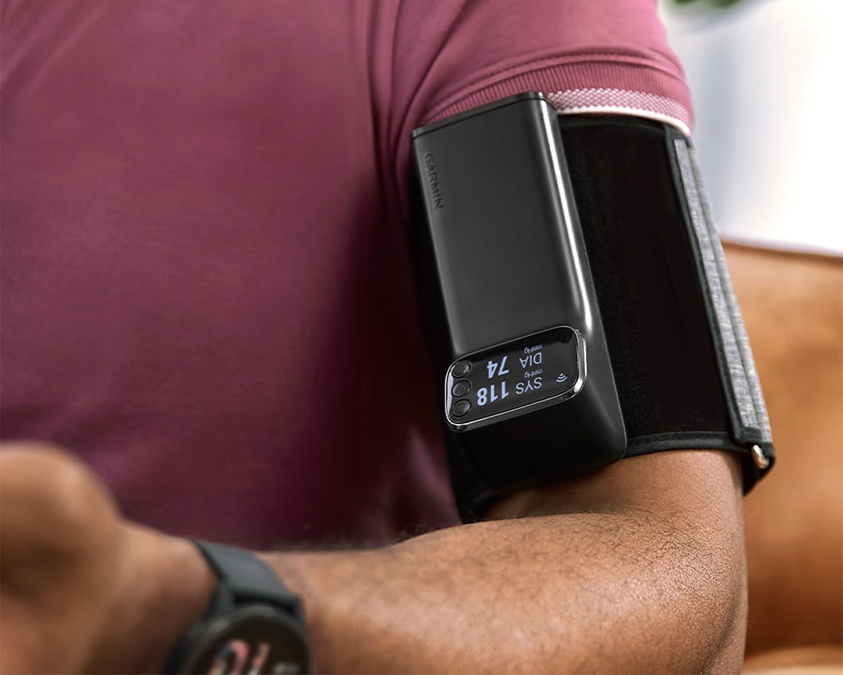 Garmin Index BPM smart blood pressure monitor cuff shown on the upper arm displaying blood pressure and pulse readings